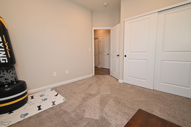 unfurnished bedroom with light carpet, a closet, and baseboards