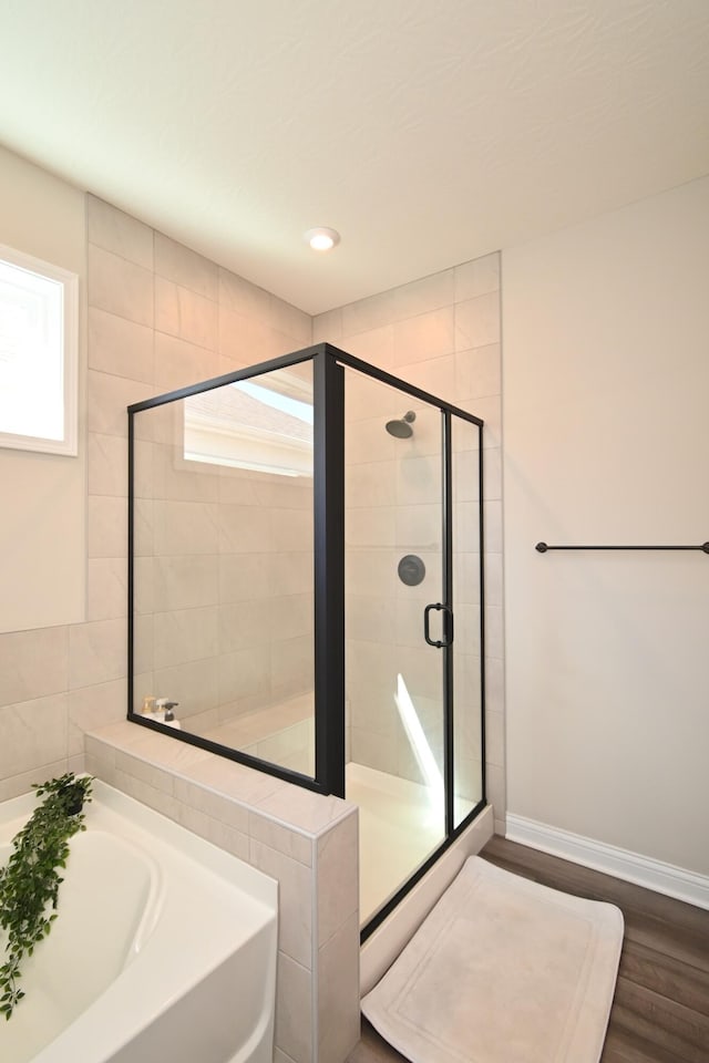 bathroom with a garden tub, recessed lighting, wood finished floors, baseboards, and a stall shower