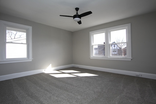 carpeted spare room with ceiling fan, plenty of natural light, and baseboards