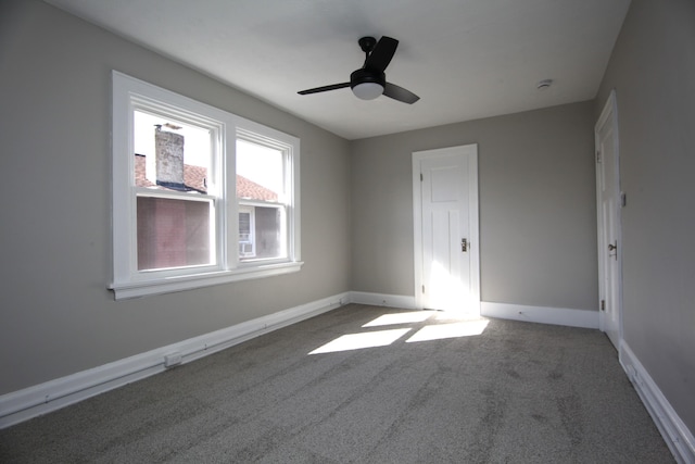 carpeted spare room featuring ceiling fan and baseboards