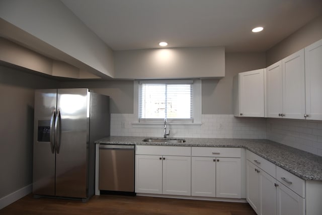 kitchen with decorative backsplash, light stone countertops, stainless steel appliances, white cabinetry, and a sink