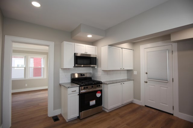 kitchen with white cabinets, light stone counters, stainless steel appliances, and decorative backsplash