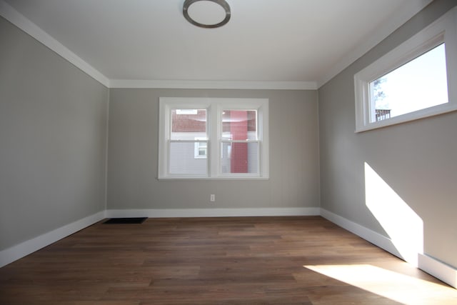 spare room featuring plenty of natural light, crown molding, and wood finished floors