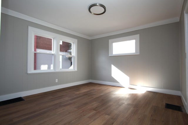 spare room with ornamental molding, dark wood-type flooring, and visible vents