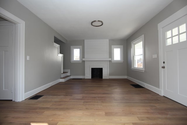 unfurnished living room featuring light wood-style floors, baseboards, a fireplace, and visible vents