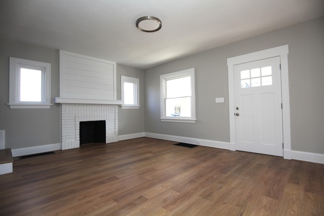 foyer with a fireplace, wood finished floors, visible vents, and baseboards