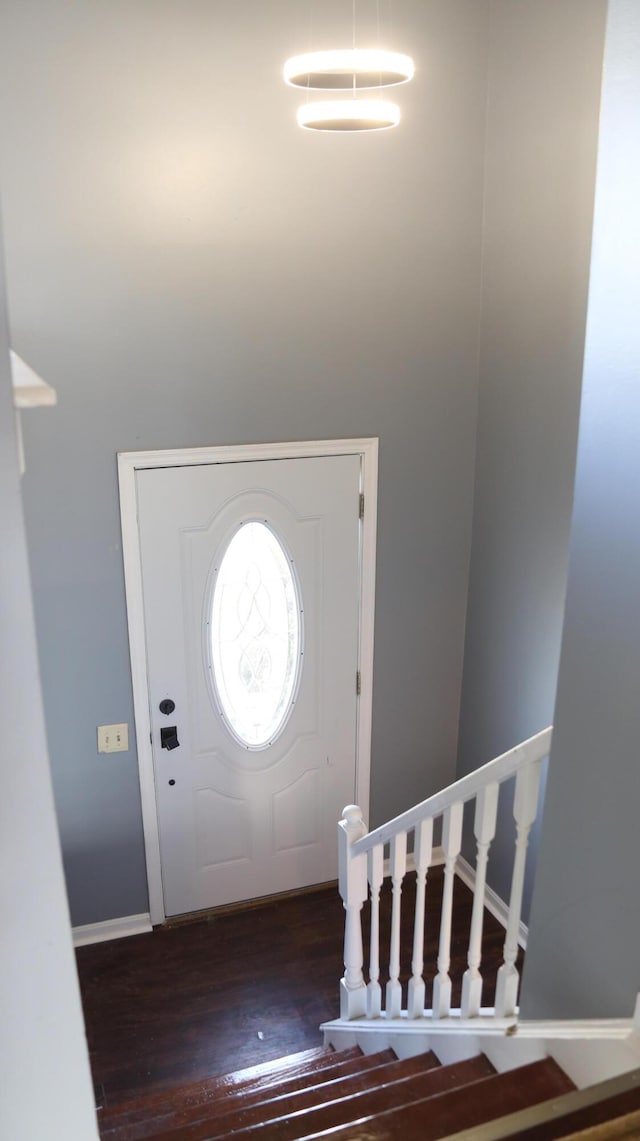 entryway with baseboards, wood finished floors, and stairs