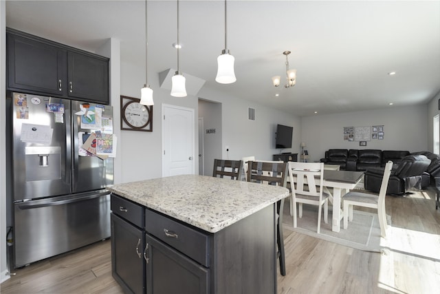 kitchen featuring a kitchen island, open floor plan, hanging light fixtures, light wood finished floors, and stainless steel fridge