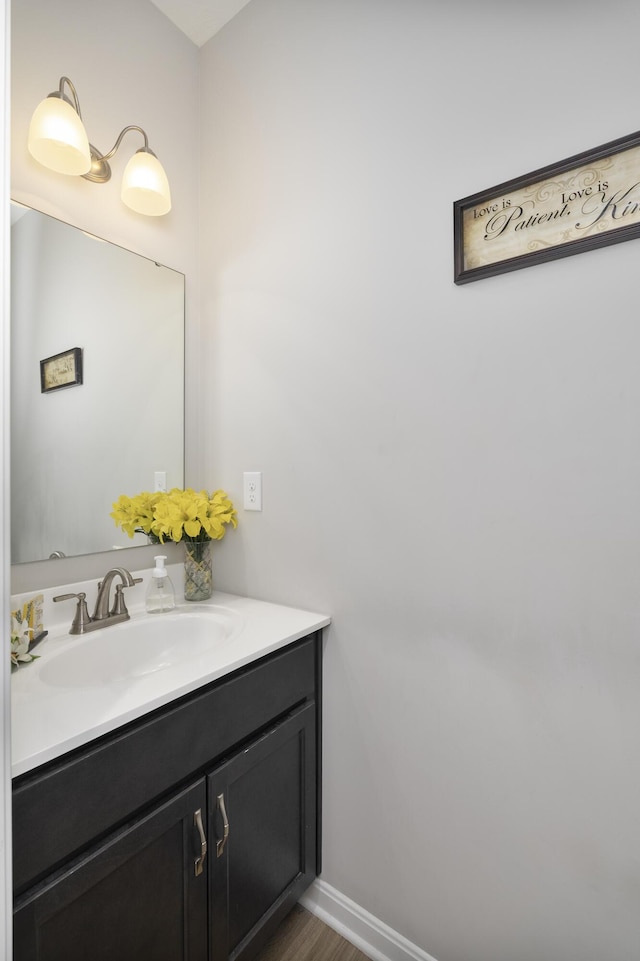 bathroom with wood finished floors, vanity, and baseboards