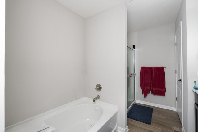 bathroom with baseboards, wood finished floors, a garden tub, an enclosed shower, and vanity