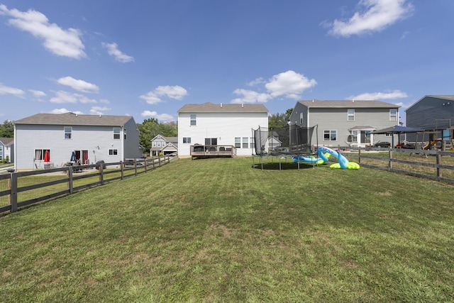 view of yard with a fenced backyard, a trampoline, and a wooden deck