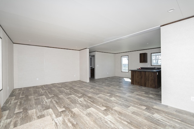 unfurnished living room featuring light wood finished floors and ornamental molding