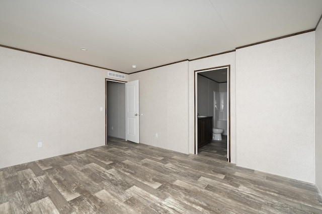 empty room featuring visible vents, wood finished floors, and ornamental molding