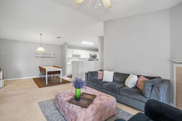 living room with visible vents, baseboards, a ceiling fan, and light colored carpet