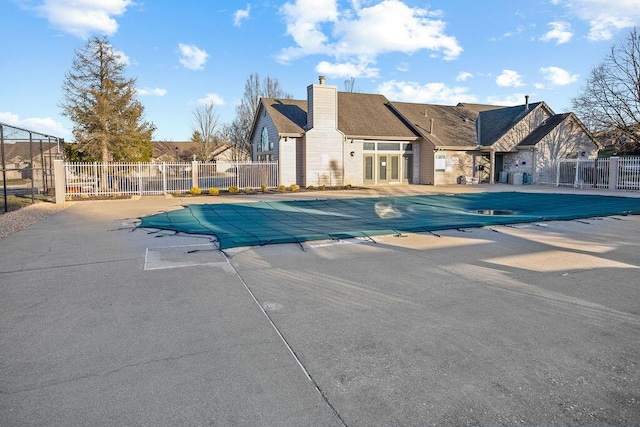 community pool with a residential view, fence, and a patio