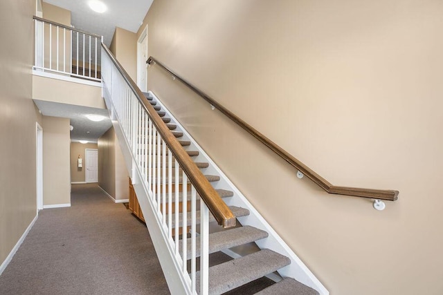 stairway with carpet floors, a high ceiling, and baseboards