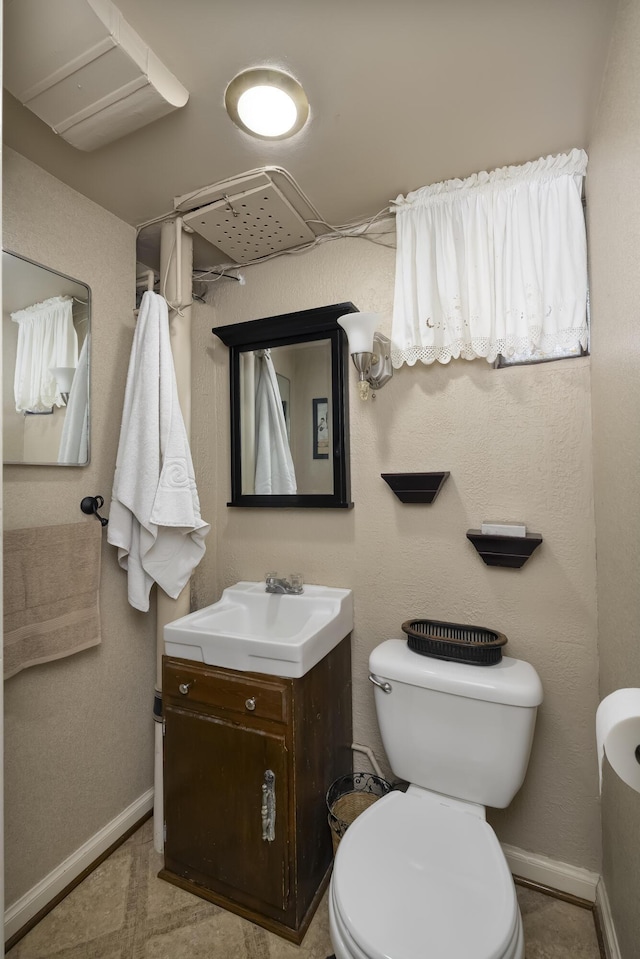 bathroom featuring toilet, baseboards, and vanity