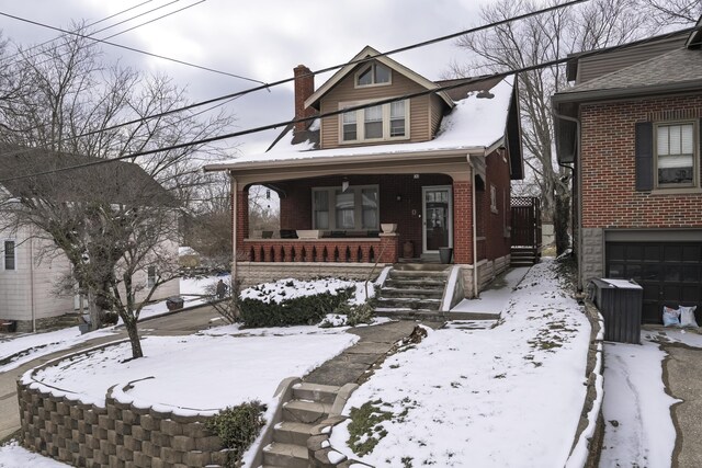 view of front of property featuring a chimney, a porch, and brick siding