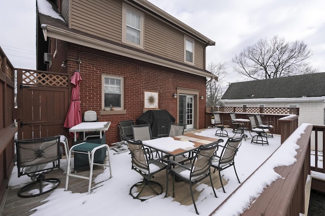 snow covered deck featuring fence, outdoor dining area, and area for grilling