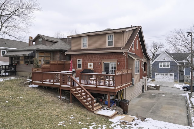 snow covered property featuring a garage, a lawn, roof with shingles, a wooden deck, and brick siding