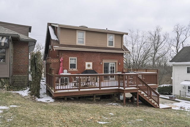 rear view of house featuring brick siding, roof with shingles, a lawn, and a wooden deck