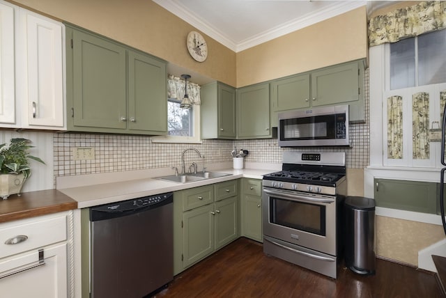 kitchen featuring green cabinets, appliances with stainless steel finishes, a sink, and ornamental molding