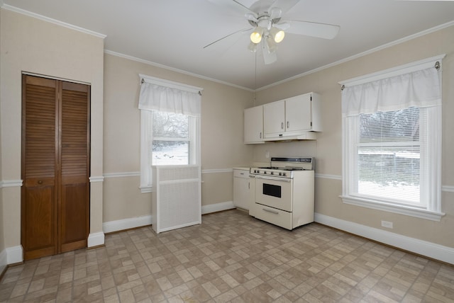 kitchen featuring baseboards, white gas stove, crown molding, and white cabinets