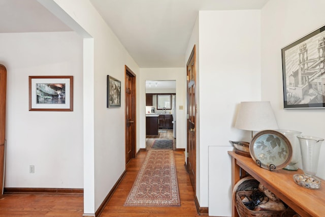 corridor featuring baseboards and wood finished floors