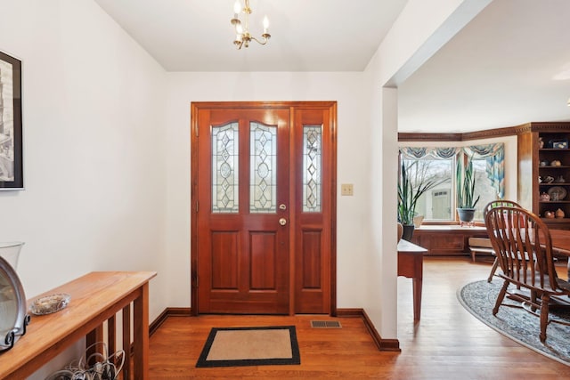 foyer with an inviting chandelier, baseboards, visible vents, and light wood finished floors