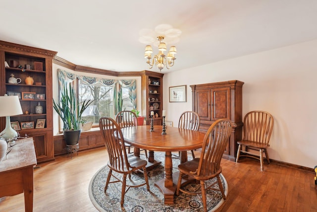 dining area featuring a chandelier, baseboards, and wood finished floors