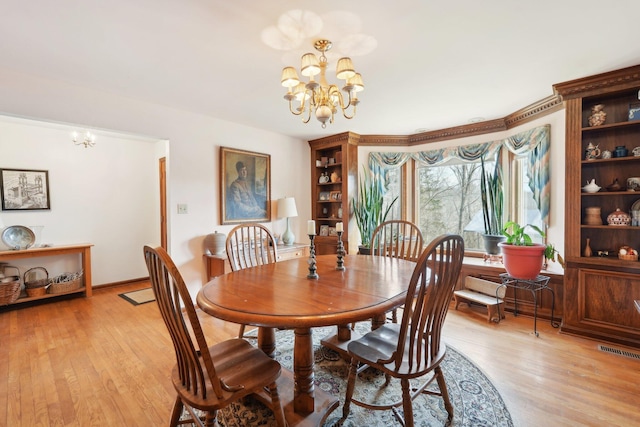 dining space featuring a chandelier, light wood finished floors, visible vents, and baseboards