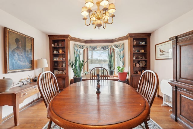 dining room featuring light wood finished floors, baseboards, and an inviting chandelier