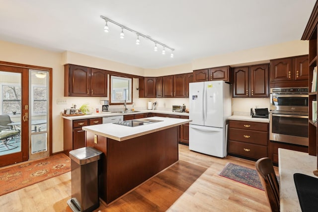 kitchen featuring white appliances, a kitchen island, light countertops, and light wood-style floors