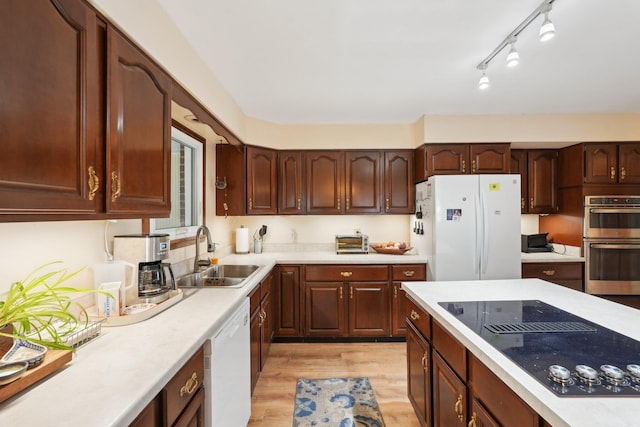 kitchen with white appliances, light countertops, a sink, and light wood-style flooring