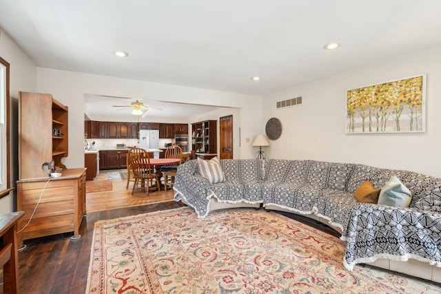 living area with ceiling fan, visible vents, dark wood-type flooring, and recessed lighting