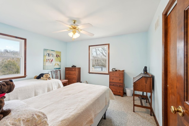 bedroom with visible vents, multiple windows, a ceiling fan, and light colored carpet