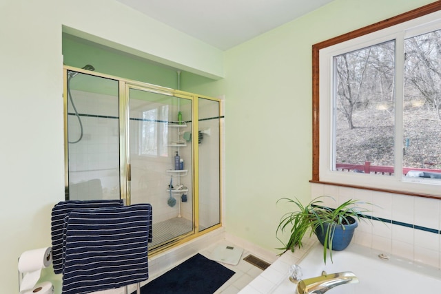 bathroom with tiled shower, a bathtub, visible vents, and baseboards