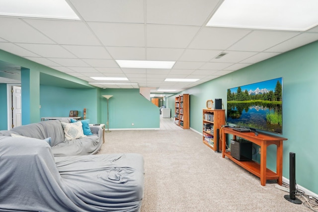 living area featuring visible vents, baseboards, a drop ceiling, and light colored carpet