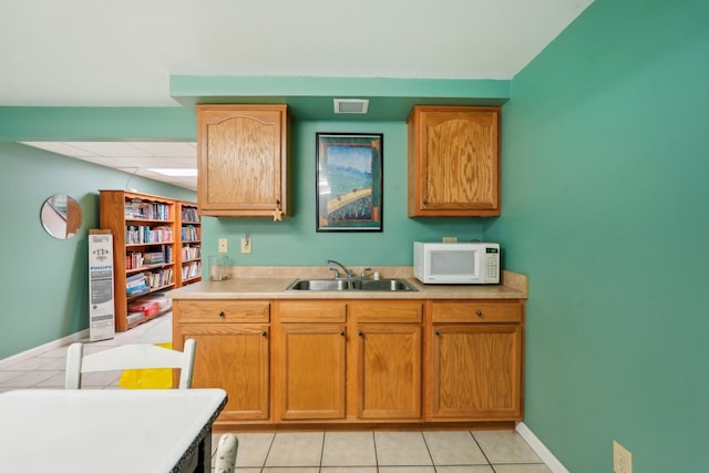 kitchen with light countertops, a sink, visible vents, and white microwave