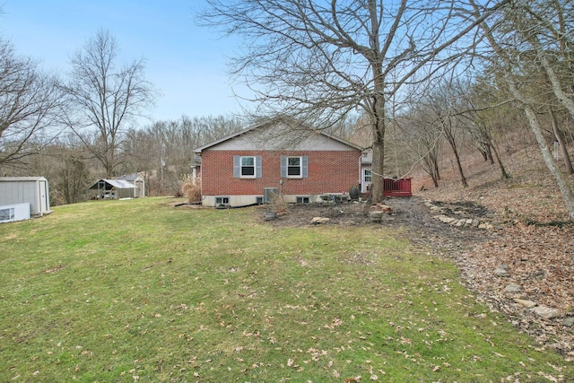 view of home's exterior with brick siding, a yard, and a wooden deck