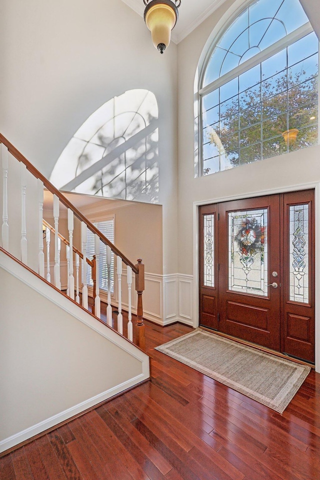 entrance foyer featuring a wealth of natural light, stairway, wood-type flooring, and a high ceiling