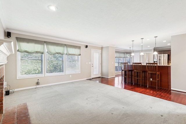 unfurnished living room featuring a wealth of natural light, dark carpet, a fireplace, and crown molding