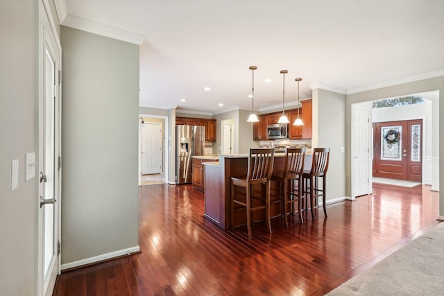 kitchen featuring dark wood-type flooring, ornamental molding, appliances with stainless steel finishes, a peninsula, and brown cabinetry