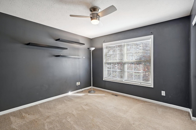 unfurnished room with a ceiling fan, baseboards, visible vents, carpet floors, and a textured ceiling