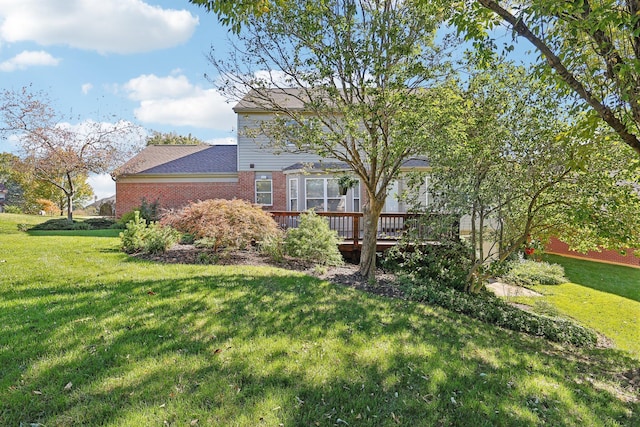 rear view of house with a lawn, brick siding, and a wooden deck