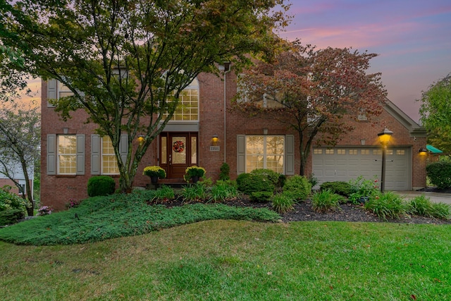 traditional-style house featuring a front lawn, an attached garage, brick siding, and concrete driveway