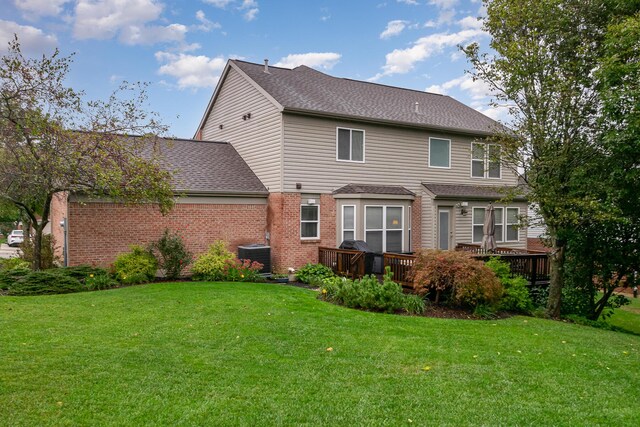 back of house with brick siding, central air condition unit, a lawn, and a wooden deck