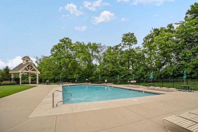 community pool with a gazebo, fence, and a patio area