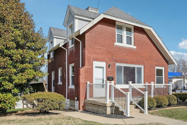 view of front of house featuring a shingled roof and brick siding