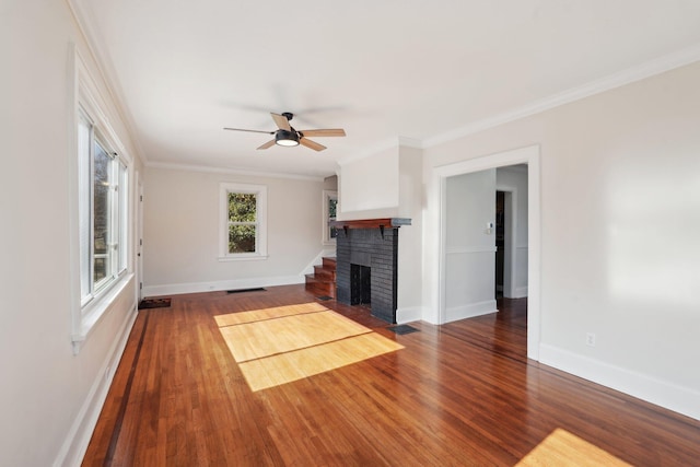 unfurnished living room with baseboards, visible vents, wood finished floors, and ornamental molding